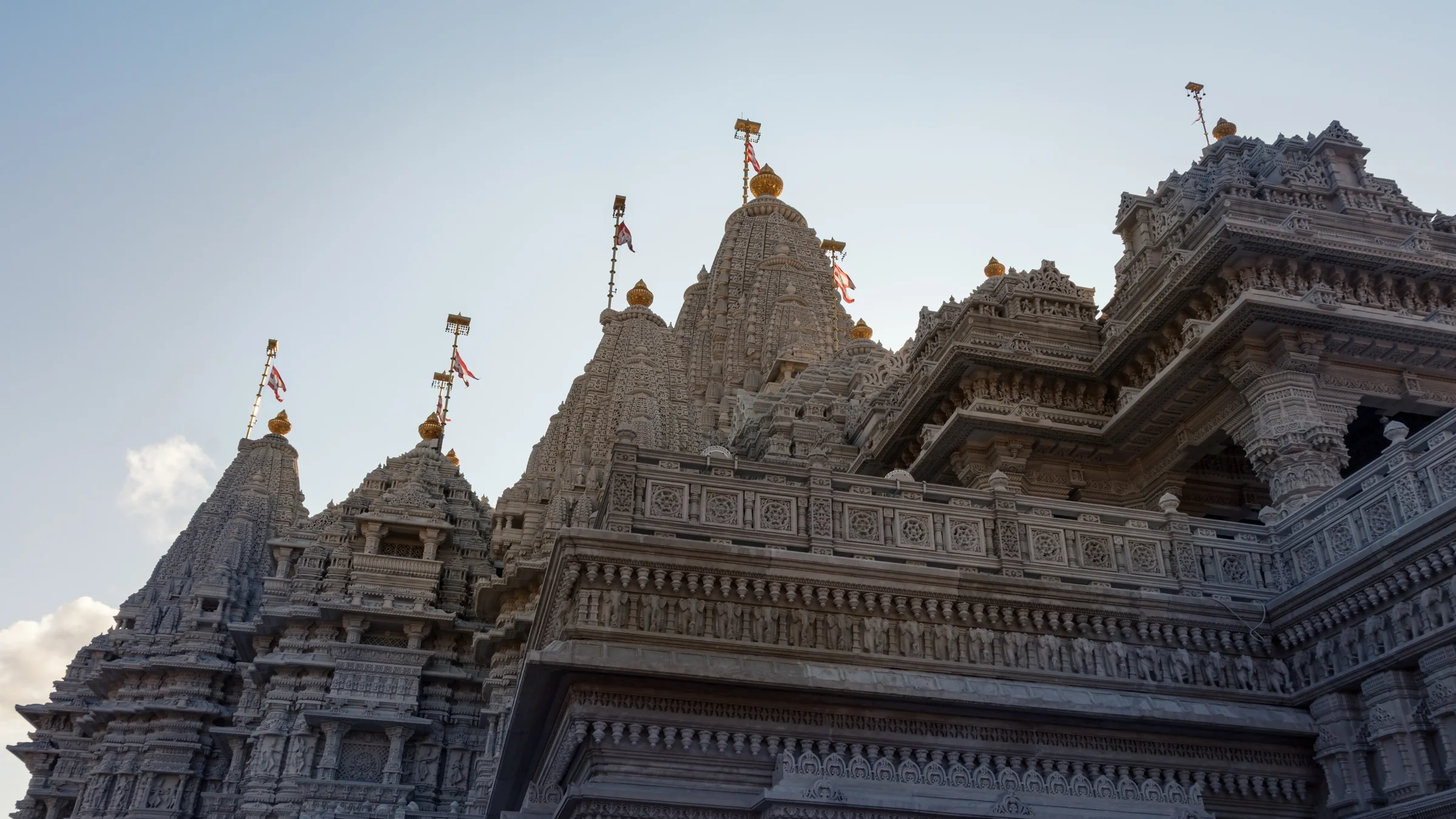 Layered temple roofs and intricate stone carvings rise against a pale blue sky.