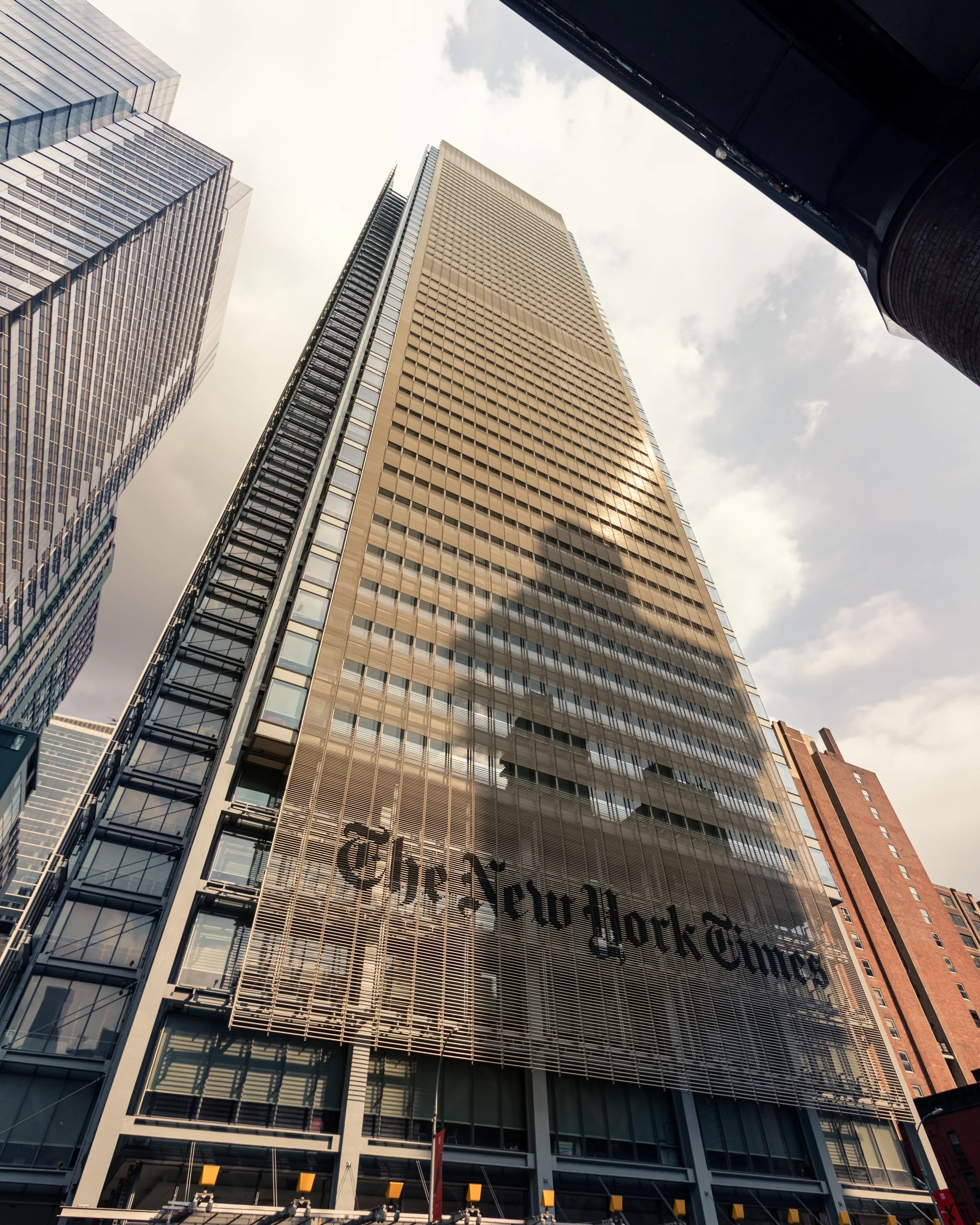 The New York Times sign marks a tall modern facade viewed from street level.