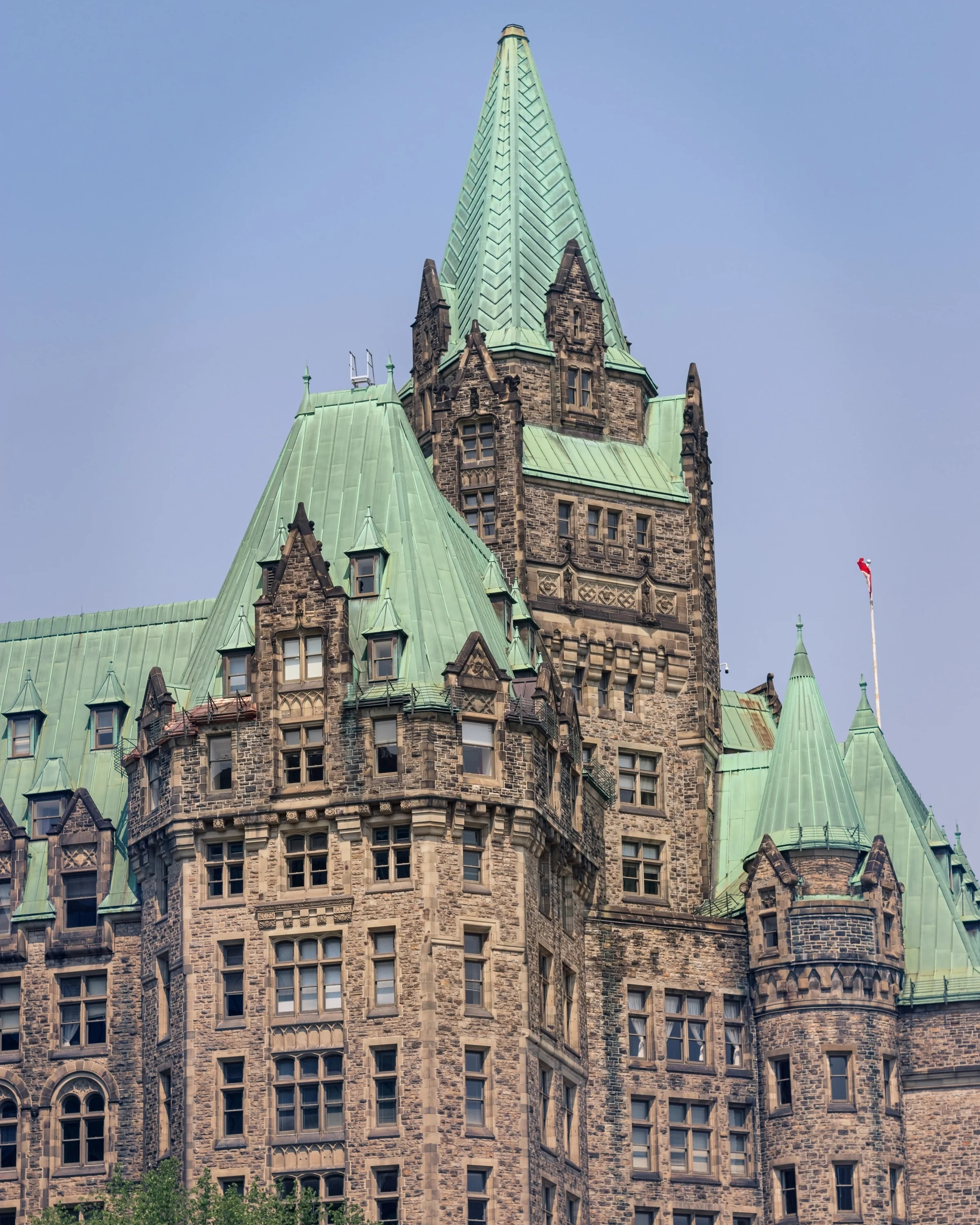 An ornate stone building rises beneath steep green roofs and decorative turrets.